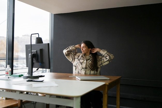 Woman Stretching Arms Upward During a Break in a Modern Office Workspace
