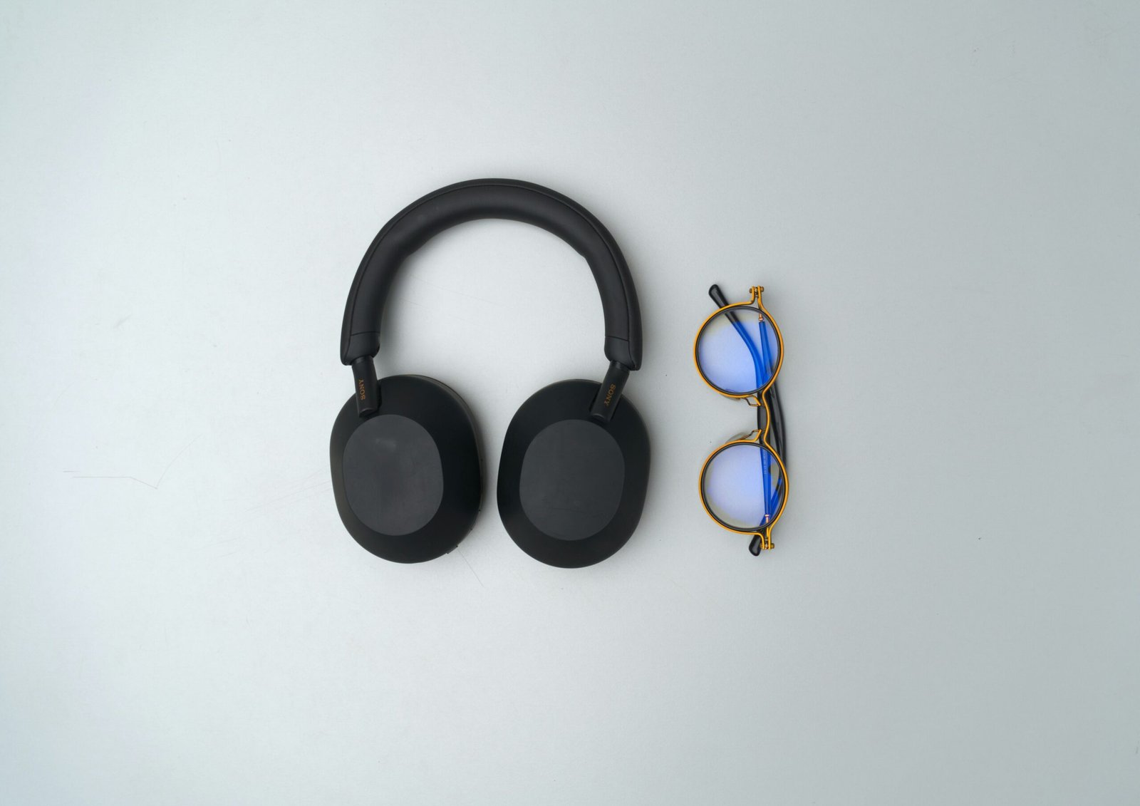 Black headphones and glasses on a light background