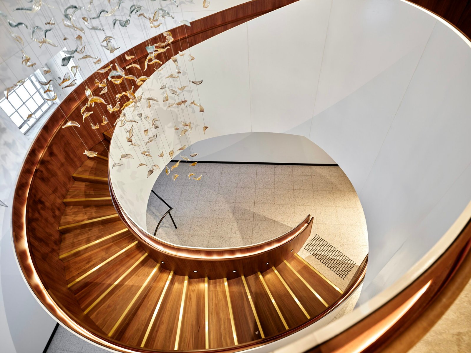 Modern spiral staircase with wooden steps and lighting.