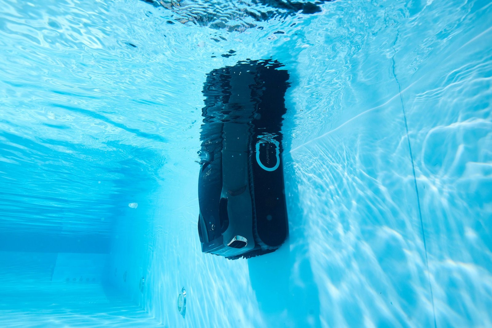 A black briefcase is submerged underwater in a pool.