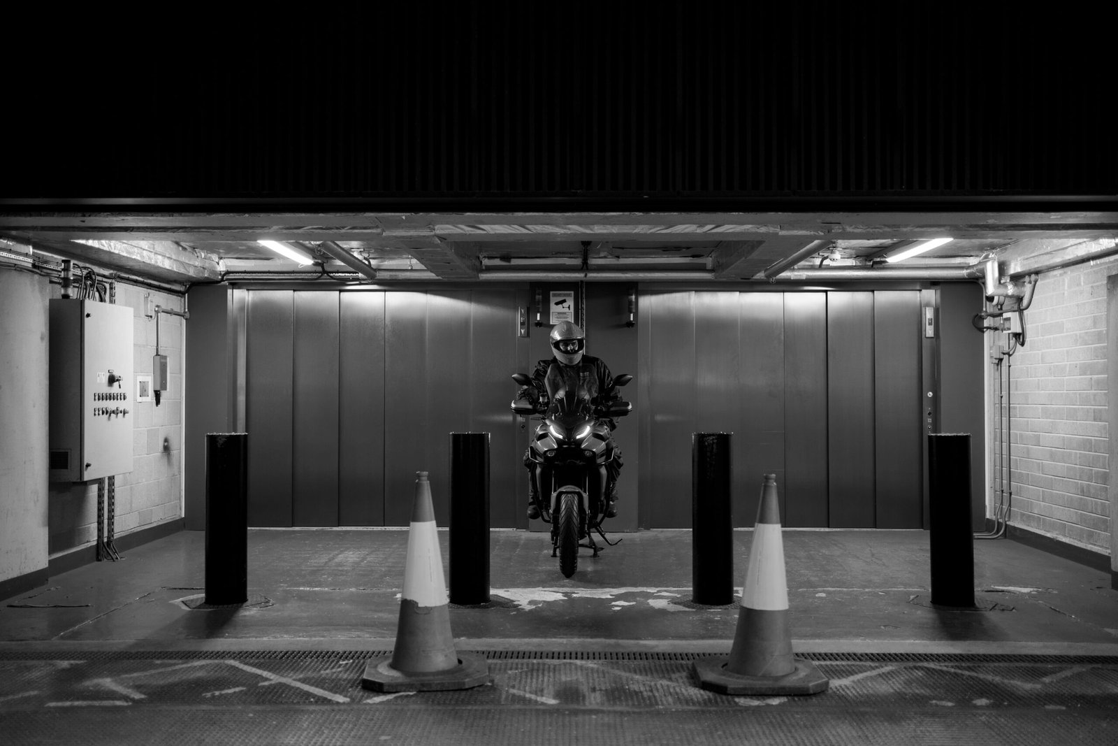Motorcyclist in a dark garage with traffic cones.