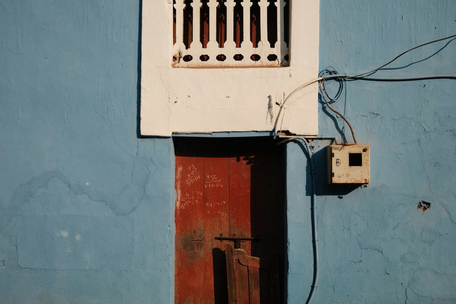Blue wall with red door and white window.