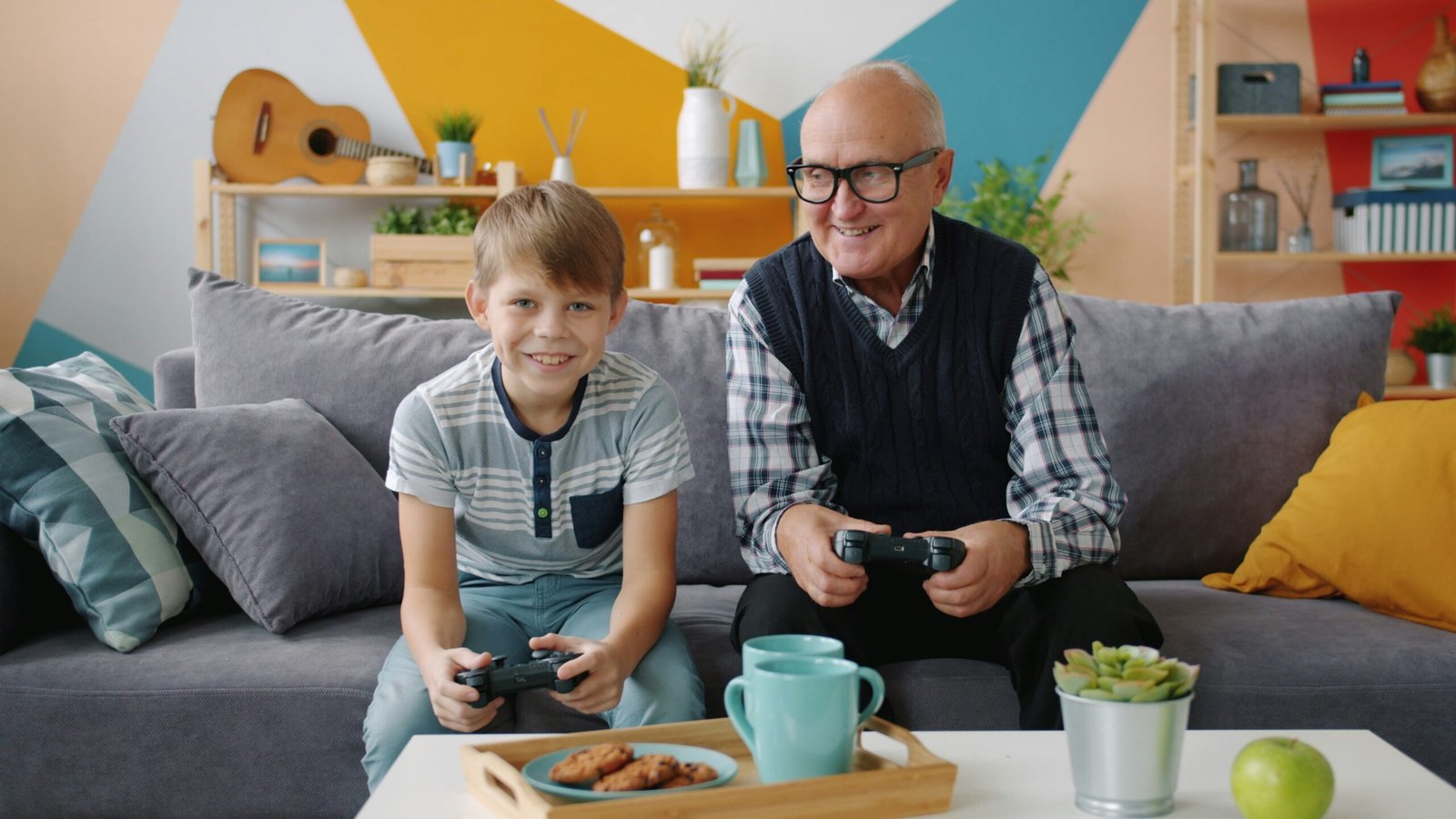 Grandfather and grandson playing video games together on couch.