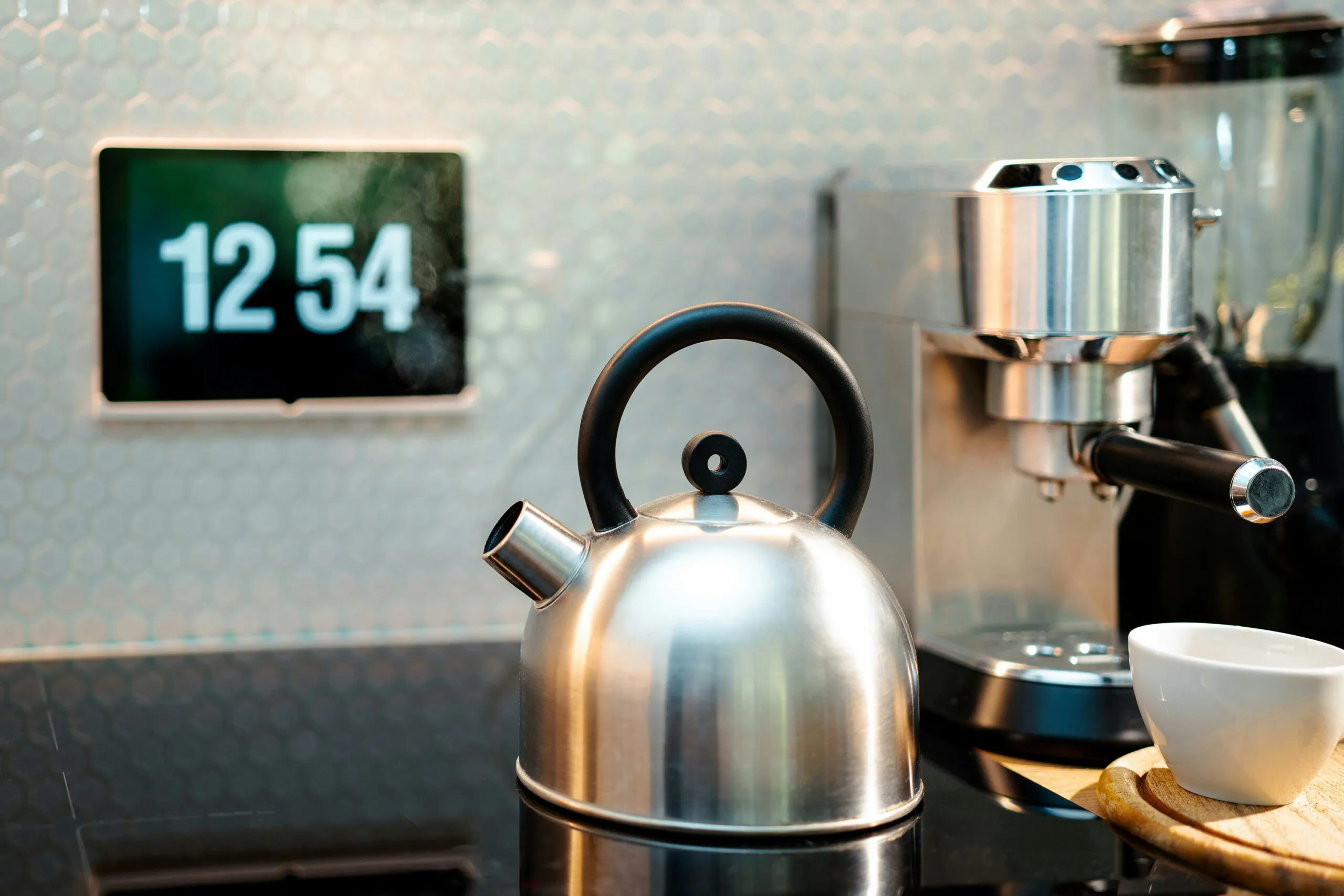 a tea kettle sitting on top of a counter next to a cup
