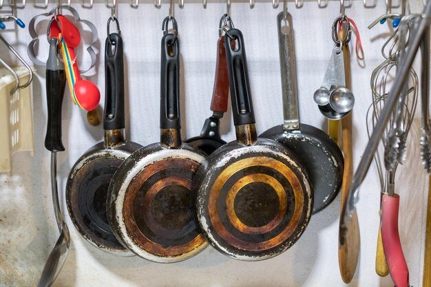Kitchenware pan and spoon hanging on rack in kitchen