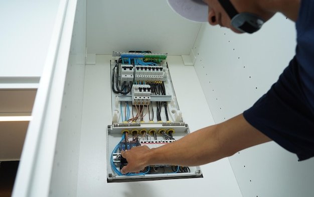Electrician working checking a switchboard with fuses