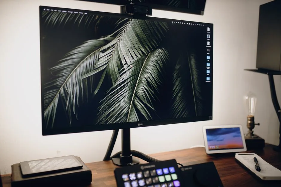 A modern desktop setup featuring a large monitor, tablet, and tech accessories for a stylish workspace.