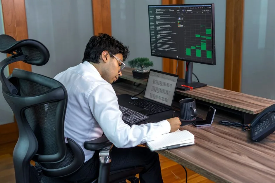 A focused professional analyzing data on computer in a modern office setting.