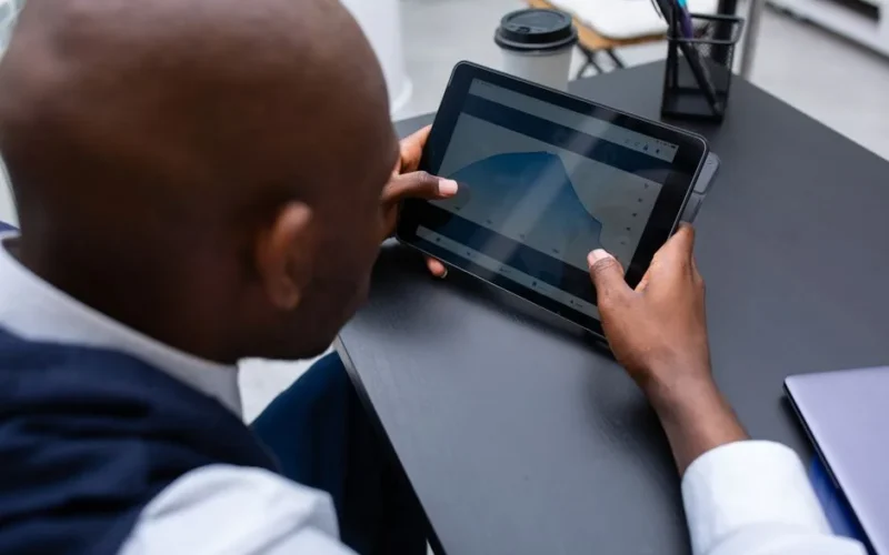 Corporate professional analyzing data and graphs on digital tablet in modern office setting.