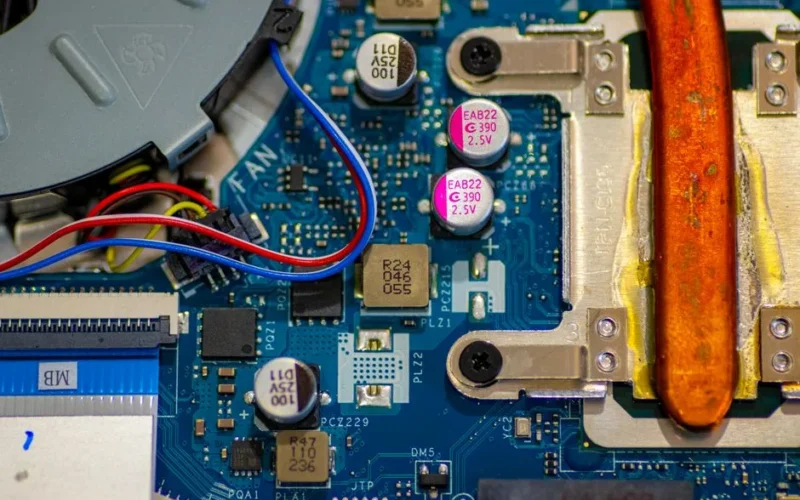 Detailed image showing circuitry and components on a computer motherboard with wires and capacitors.