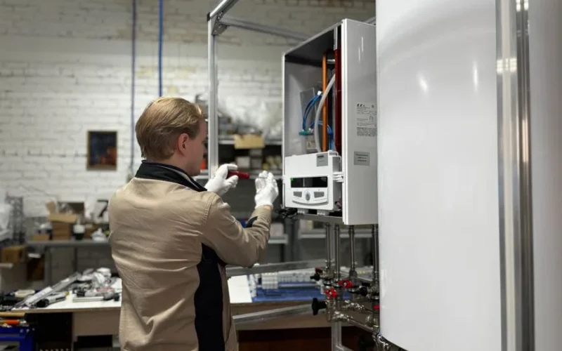 Technician inspects and repairs a heating system in an industrial workshop setting.