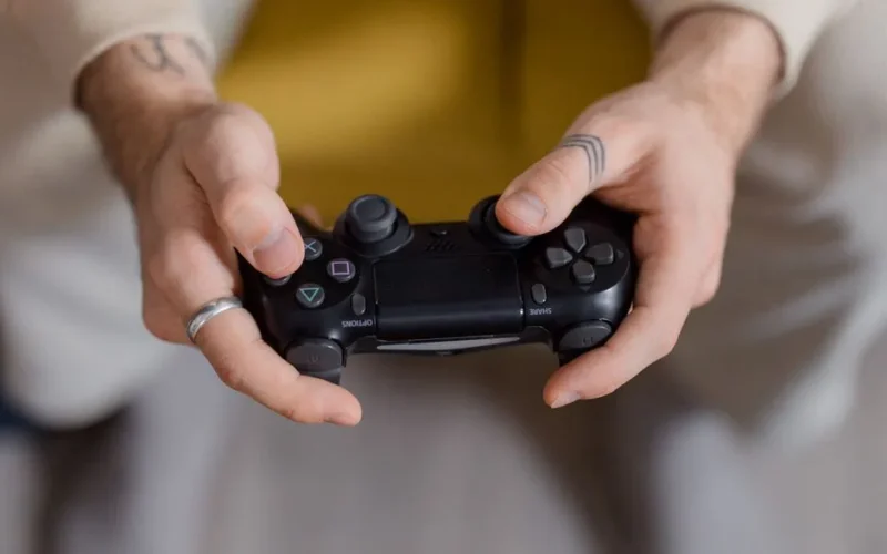 A gamer holding a black game controller, focusing on gaming and entertainment.