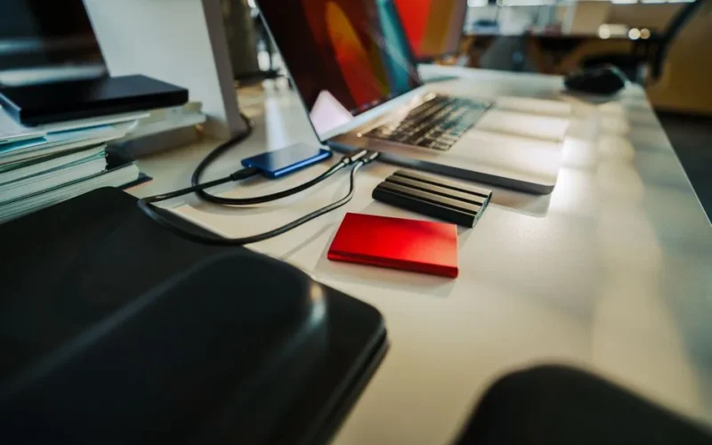 A neatly organized office desk featuring a laptop and several external hard drives, perfect for a digital workspace.