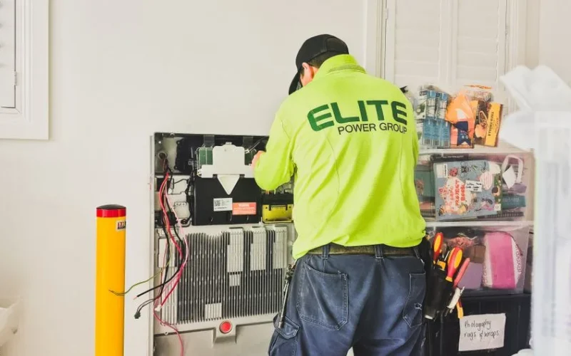 A technician from Elite Power Group installing a home battery system indoors in New South Wales, Australia.