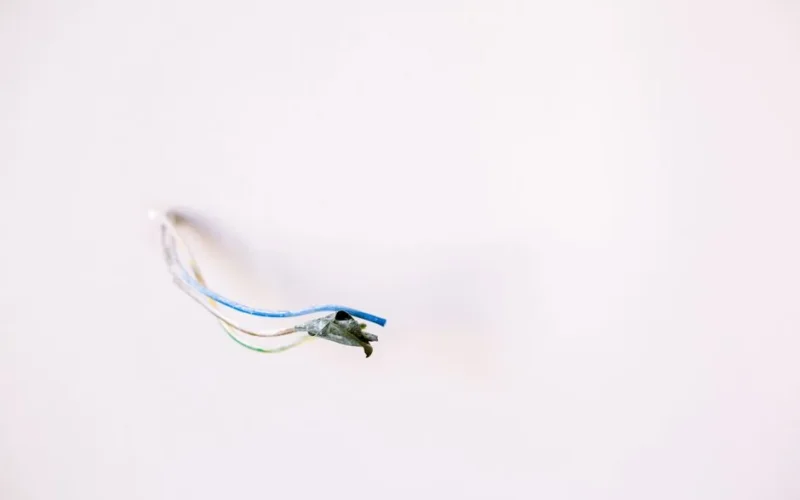 Loose electrical wires protruding from a white wall, ideal for home improvement concepts.