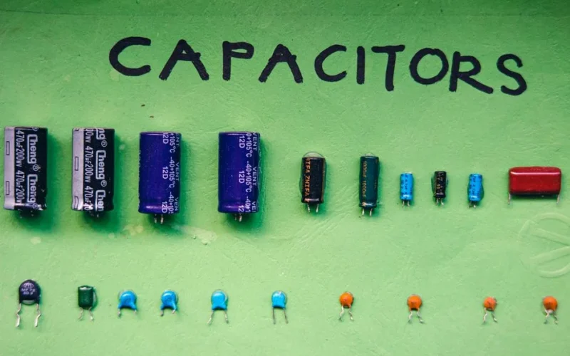 Top view layout of various capacitors for storing electrical energy of different sizes and capacities arranged on green background with inscription