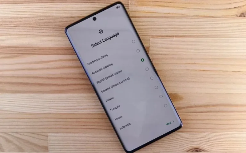 Close-up of smartphone with language selection screen on wooden table.