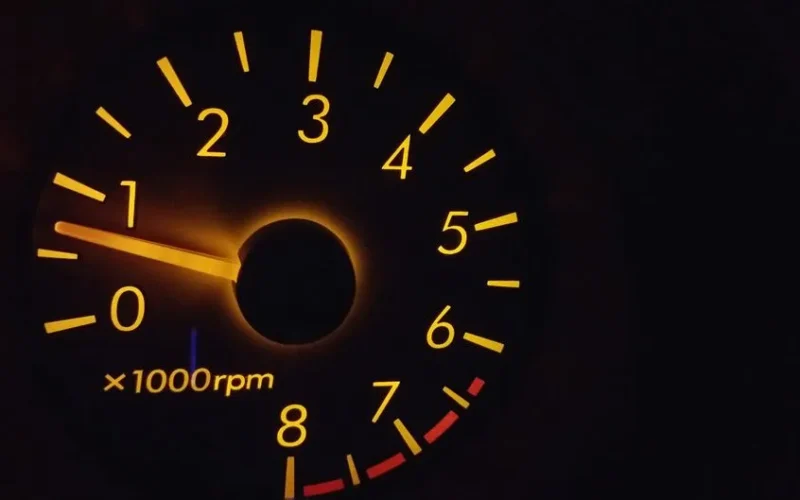 Close-up of a glowing RPM gauge with orange backlight reflecting technology theme.