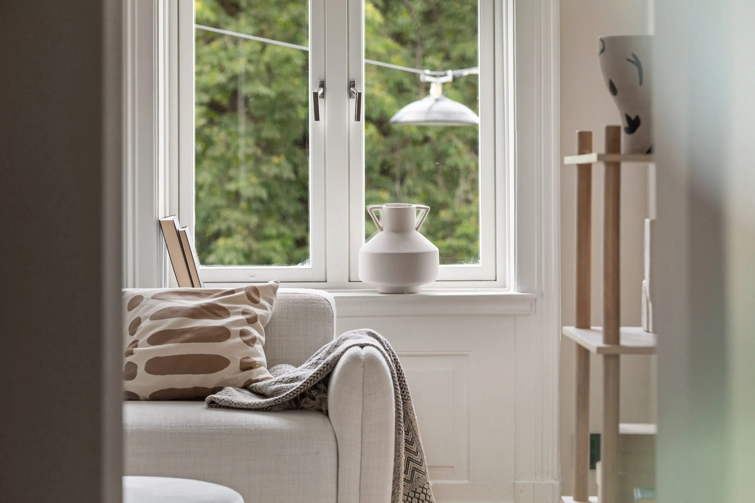 Inviting living room with a comfortable sofa, soft blanket, and view through large windows.