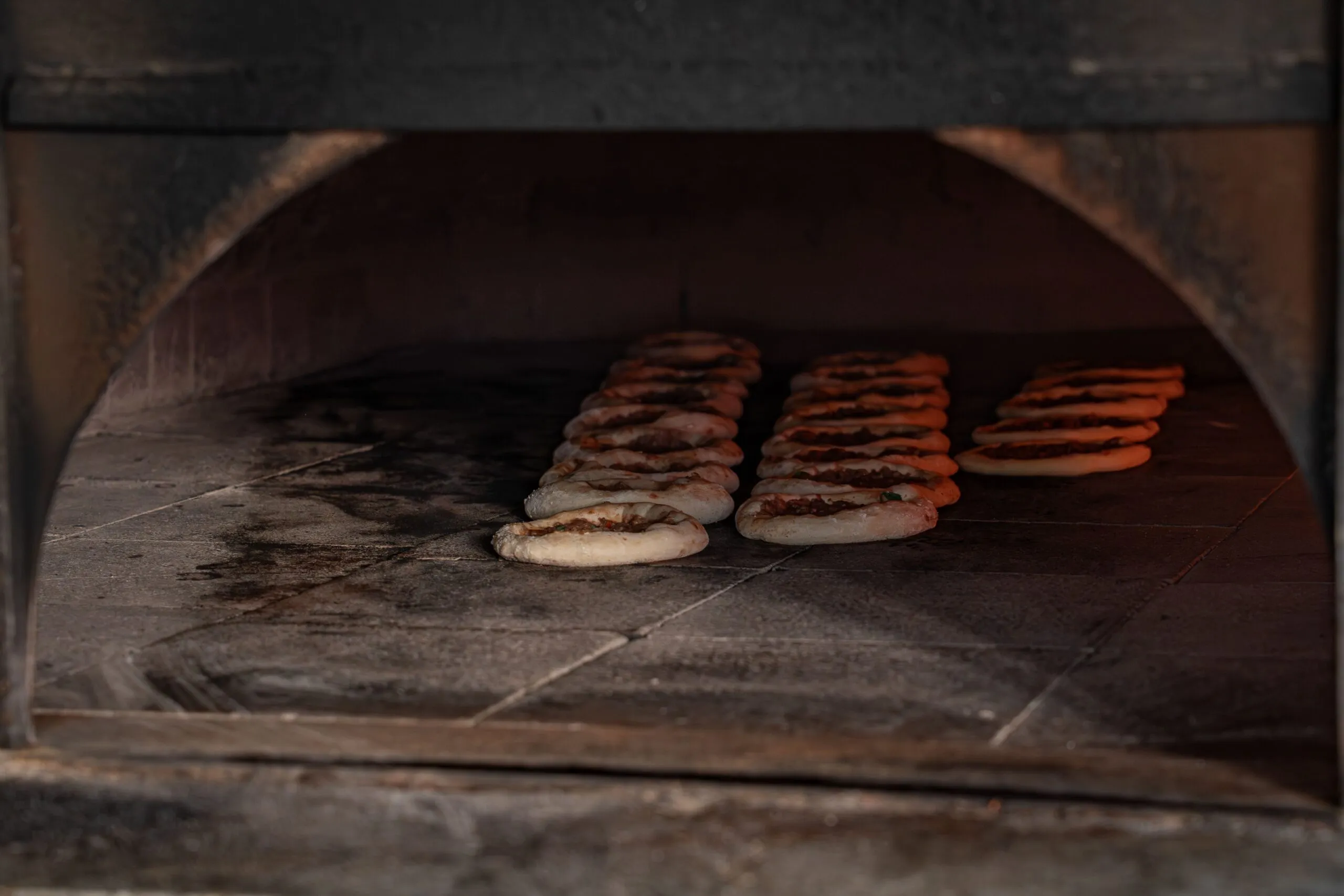 Delicious flatbreads baking inside a rustic stone oven showcase traditional culinary methods.