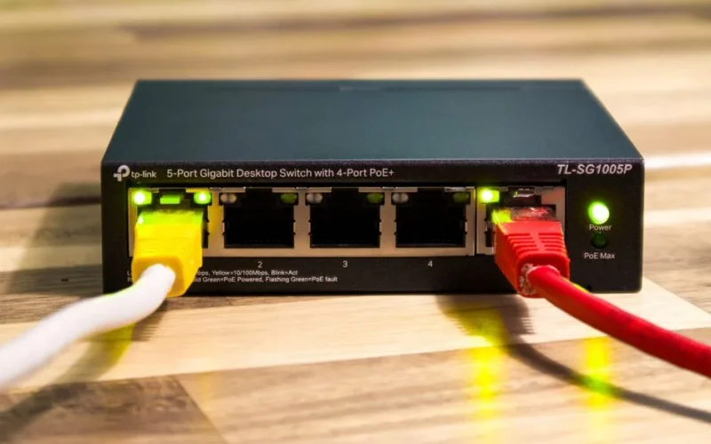 Close-up of a TP-Link Ethernet switch with yellow, red, and white cables connected.