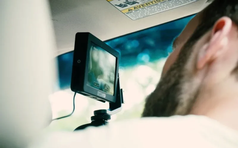 Adult male using dashboard camera while driving. Focus on modern technology and screen.