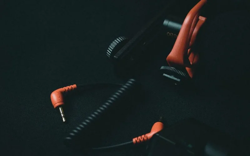 Close-up view of an orange coiled audio cable and adapter on dark background.