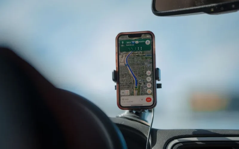 A smartphone with GPS navigation app mounted on a car dashboard during a road trip.