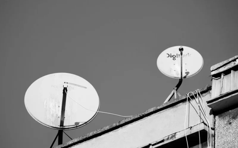Monochrome image of two satellite dishes on a rooftop, representing communication technology.
