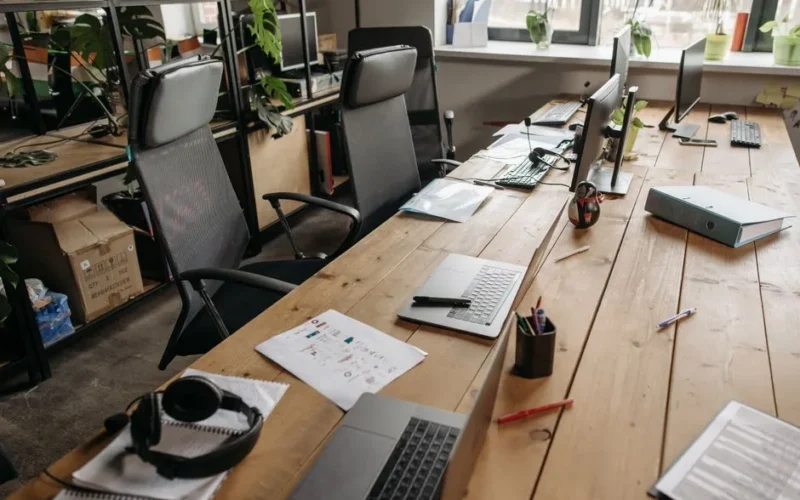 Spacious co-working office with wooden desks, laptops, and modern chairs.