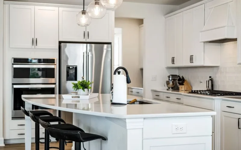A sleek modern kitchen with white cabinets, elegant lighting, and stainless steel appliances, providing a clean and contemporary look.