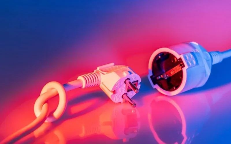 Close-up of electric plug and socket with vibrant lighting, showcasing technology and energy concepts.
