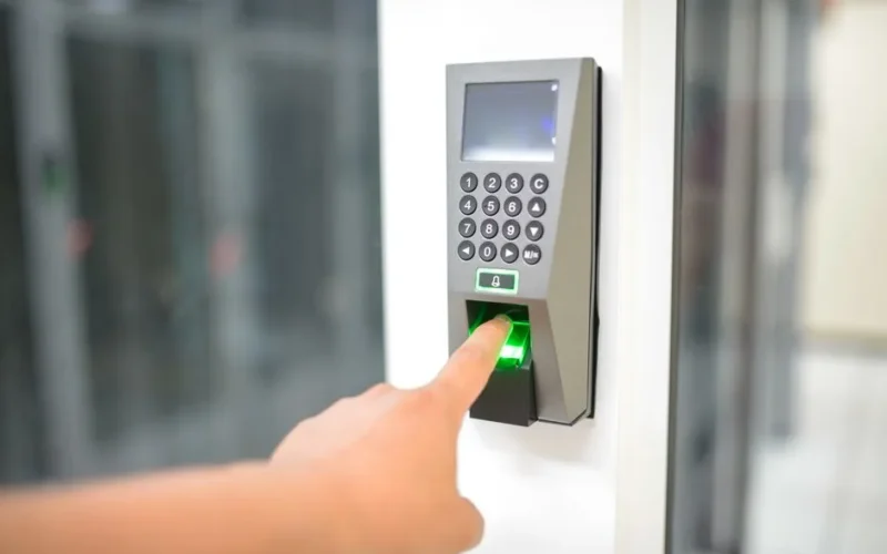 A person uses a fingerprint scanner for secure entry in a business setting.
