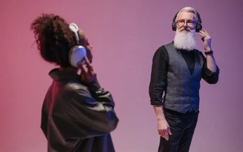 Elderly man and woman with headphones enjoying music in modern studio.
