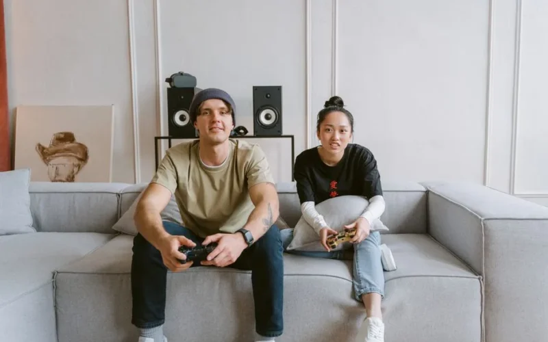 Man and woman playing video games on a couch, conveying a relaxed and fun atmosphere.