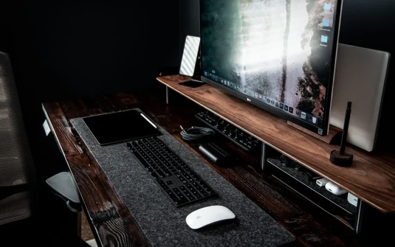 High angle of contemporary workplace with modern devices including desktop with keyboard and netbook smartphone and computer mouse with tablet