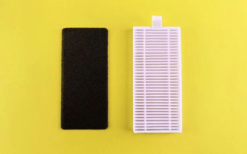 Black foam filter and white air filter on bright yellow backdrop showcasing air purification essentials.