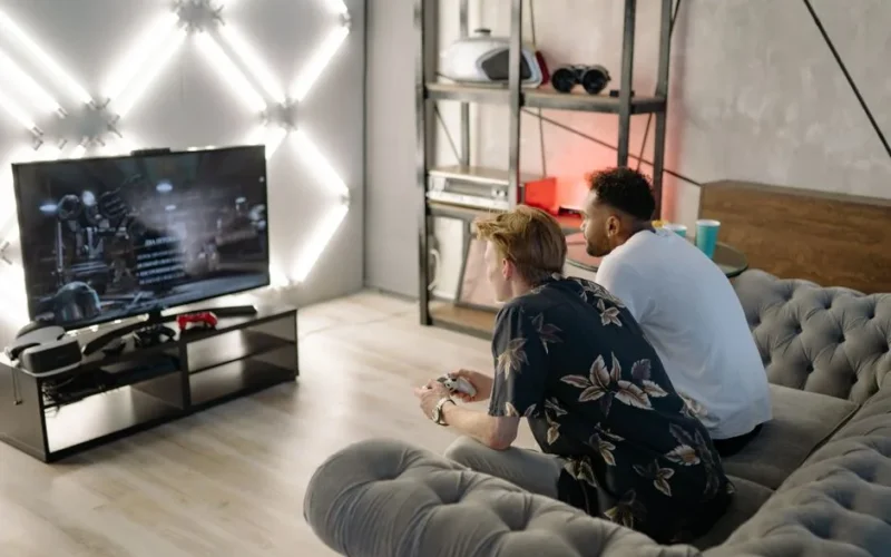 Two young men gaming together in a stylish modern living room with a large TV.
