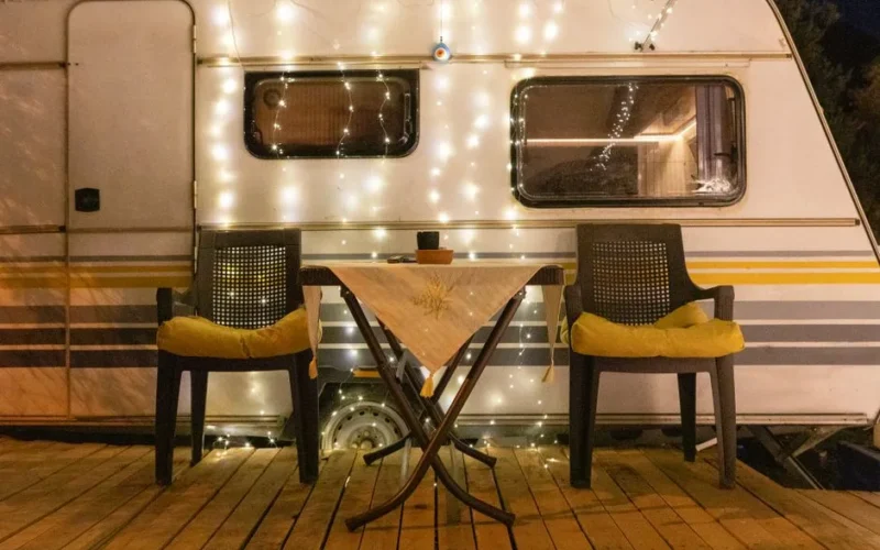 A warmly lit camper van setup with chairs and fairy lights, perfect for a relaxing night outdoors.