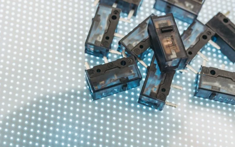 Macro photo of black electronic switches on illuminated LED surface, highlighting technology components.