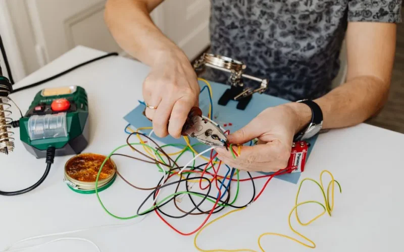 A technician precisely cuts and organizes colorful wires using pliers, showcasing expertise in wiring tasks.