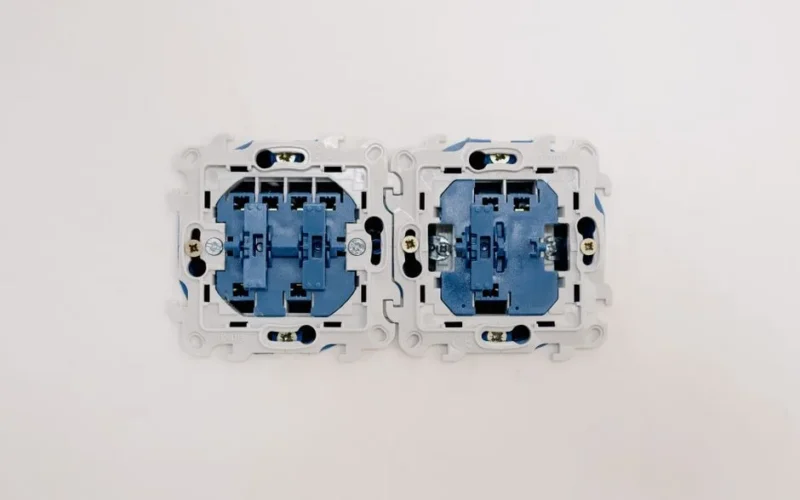 Opened electric switches without caps placed on light wall in apartment during repair works