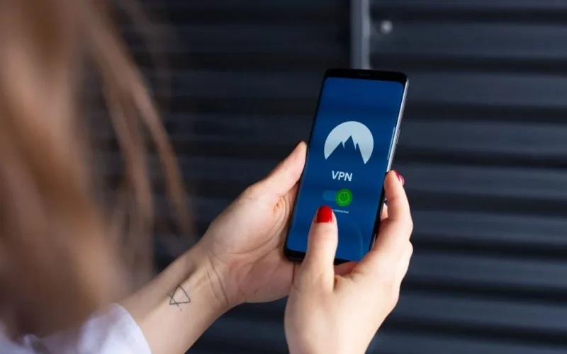 Close-up of a woman's hands using a VPN app on a smartphone, emphasizing digital security.