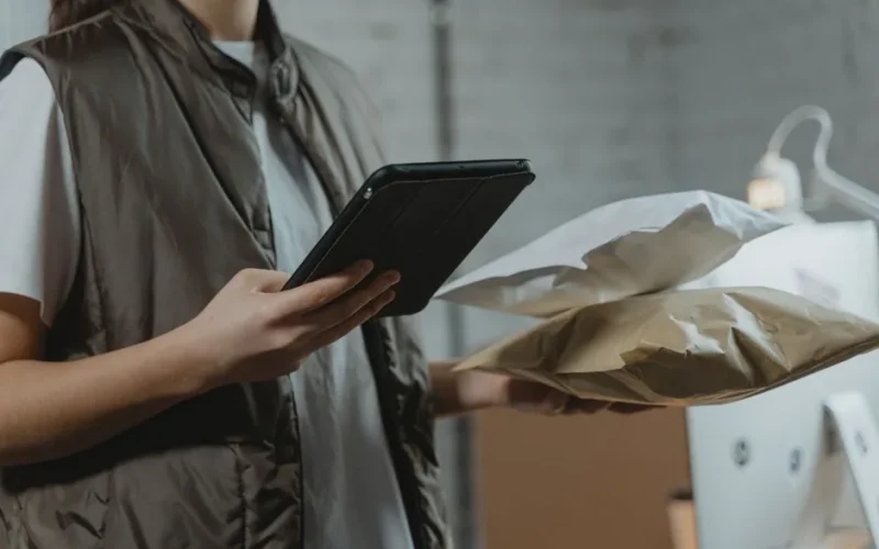 A person using a tablet to manage packages in an indoor setting, highlighting technology and logistics.