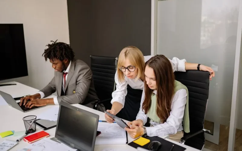 Business team collaborating in a modern office setting with laptops and tablets.