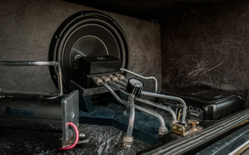 Close-up of an intricate car audio and hydraulic setup with metal components.