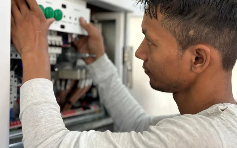 Focused electrician adjusting circuit breaker panel. Technology and skill in action.