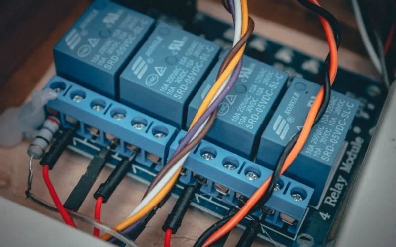 Blue relay modules with colorful wires connected on an electronic board.