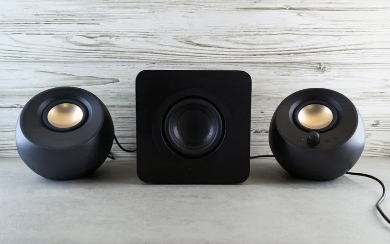 Black spherical speakers and subwoofer arranged on a stylish textured surface, perfect for a music-themed setting.