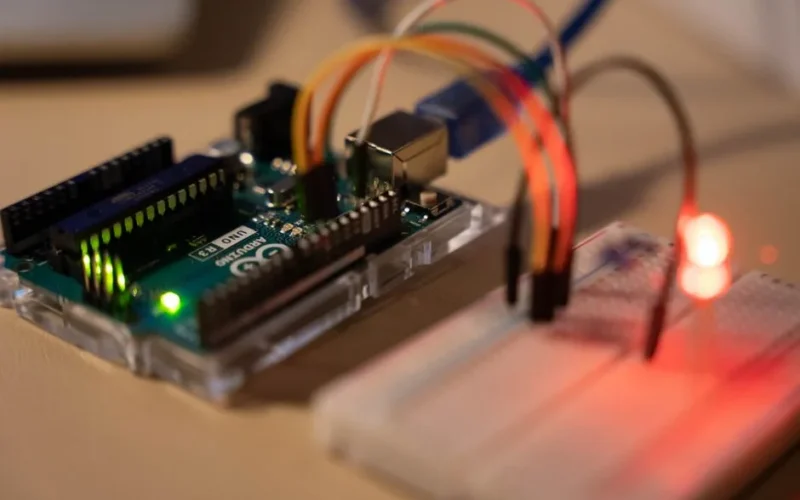 Close-up of Arduino microcontroller connected to a breadboard with a glowing LED.